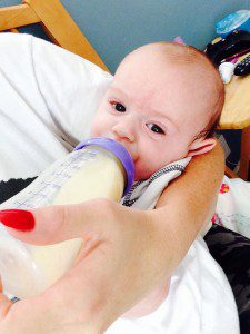 Asher taking a bottle of donor milk from his nanny