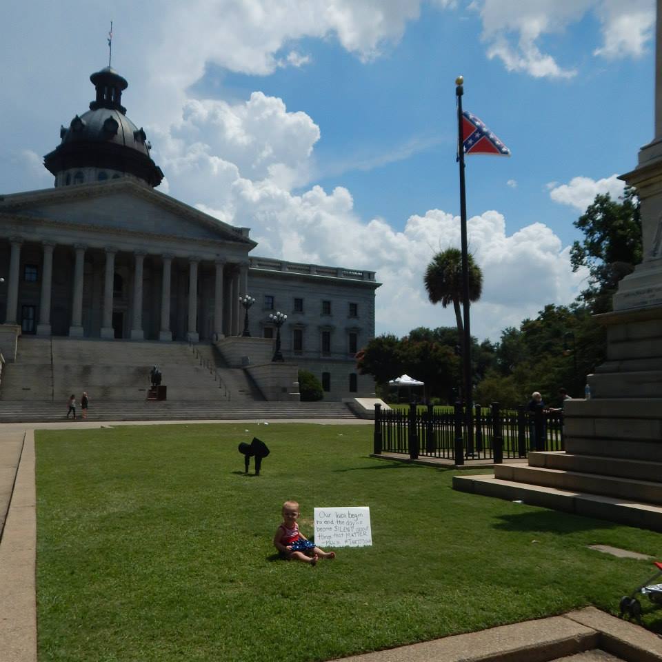 Heidi in front of the South Carolina State House in an American Flag dress. This was before the Confederate Flag was removed. The sign says, "Our lives begin to end the day we become SILENT about things that MATTER. - MLK Jr. #takeitdown