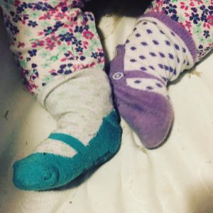 One blue sock and one purple sock on a baby's feet