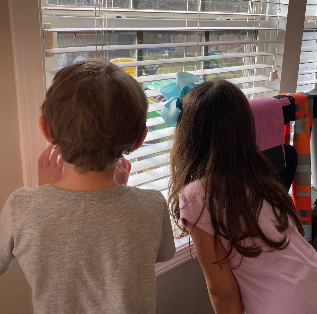 Author's son on the left and one of his friends, peeking through the blinds of a window.